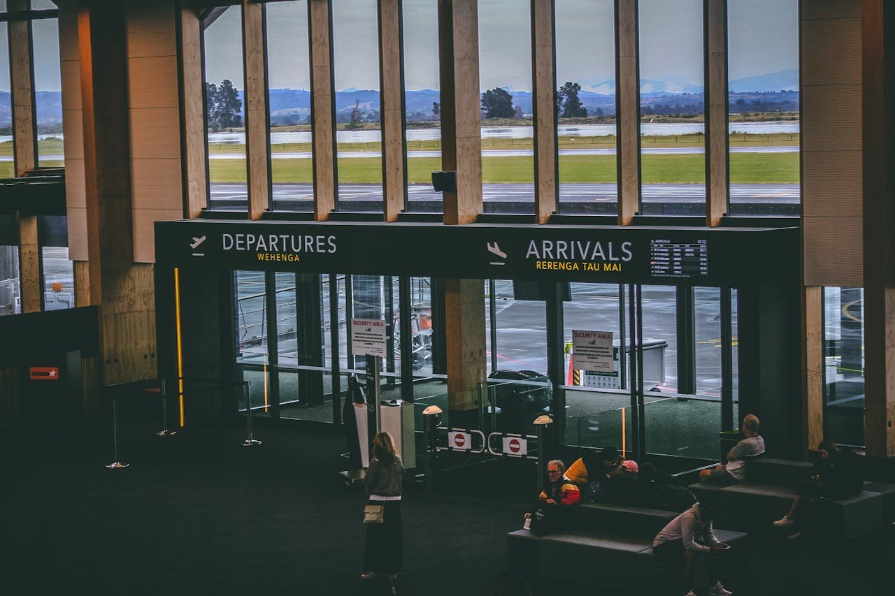 Busy airport terminal area with people, featuring departures and arrivals signs.